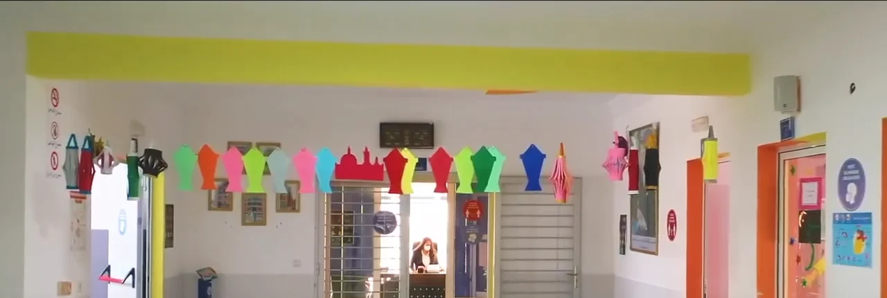 Couloir de l'établissement bordé de porte-manteaux et d'affichages colorés